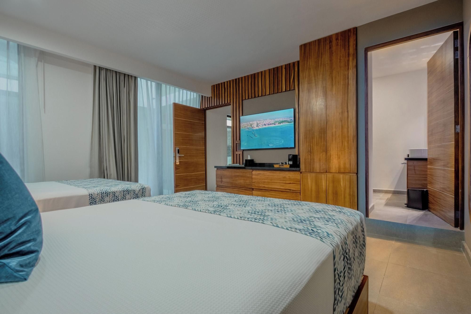 A hotel room with two beds, a TV, and a wooden wardrobe.