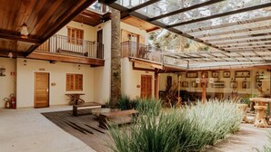 A spacious outdoor area with a wooden deck, a stone pillar, and a covered seating area with tables and chairs. - La Brume Pousada (Campos do Jordão)