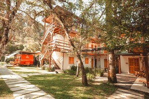 A traditional wooden house with a staircase leading to the upper floor, surrounded by lush greenery. - La Brume Pousada (Campos do Jordão)