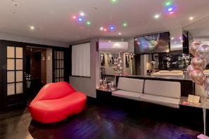 Decoração moderna com uma cadeira vermelha, sofá e área de bar com balões.