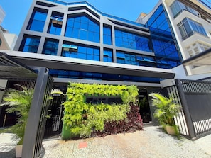 Um edifício moderno com fachada de vidro e um jardim vertical verde na entrada.