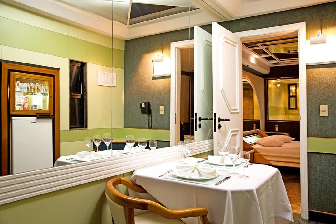 Quarto de hotel com área de refeições, cama e minibar.