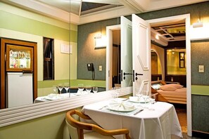 Quarto de hotel com área de refeições, cama e minibar.