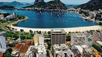 Paisagem costeira com uma montanha imponente, uma baía cheia de barcos e edifícios urbanos densos.