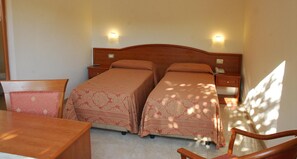 Habitación doble con dos camas, un escritorio de madera y mesitas de noche con lámparas.