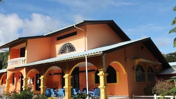 Un edificio de dos pisos con un balcón y un patio cubierto.