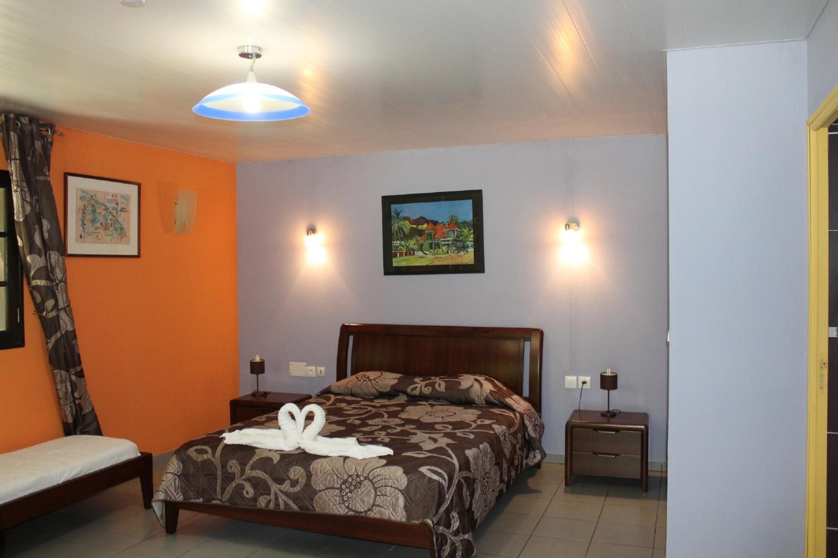 Un dormitorio con cama, mesitas de noche, una lámpara de pared y un cuadro.
