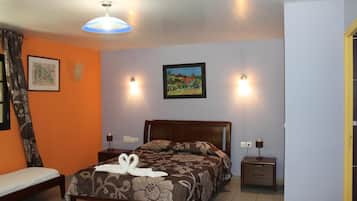 Un dormitorio con cama, mesitas de noche, una lámpara de pared y un cuadro.