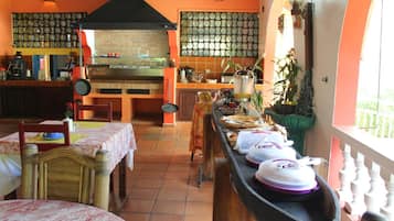 Un restaurante con horno de ladrillo, paredes con azulejos y una barra larga con productos alimenticios.