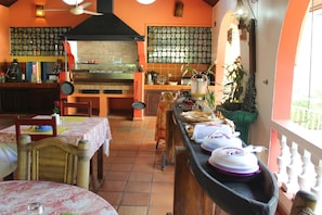 Un restaurante con horno de ladrillo, paredes con azulejos y una barra larga con productos alimenticios.