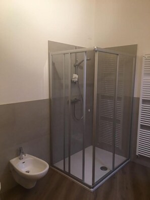 A glass-enclosed shower with a handheld showerhead and a handheld basin. - Albergo Croce D'aune (Sovramonte)