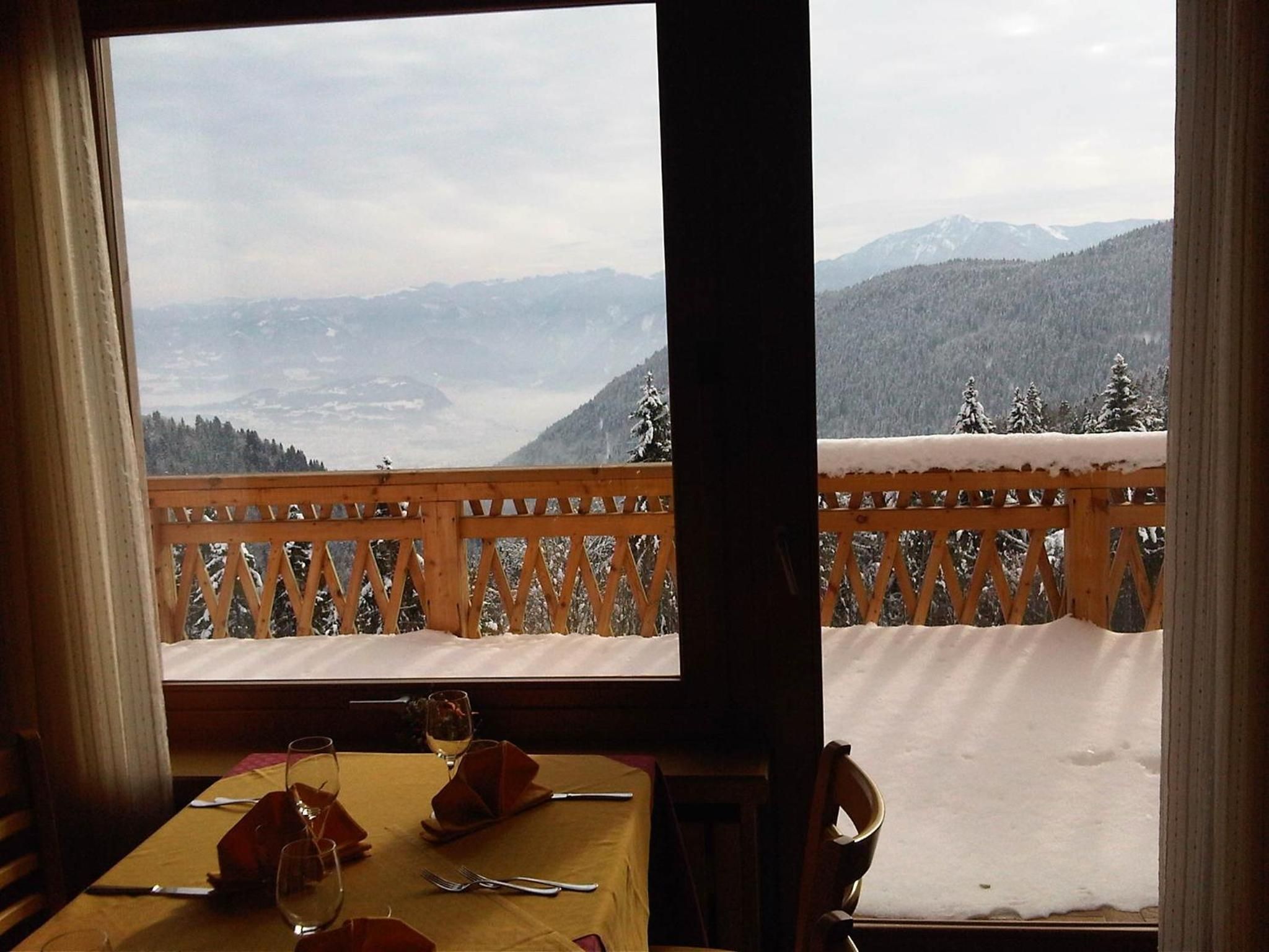 A dining table with a view of snow-covered mountains through a wooden railing.