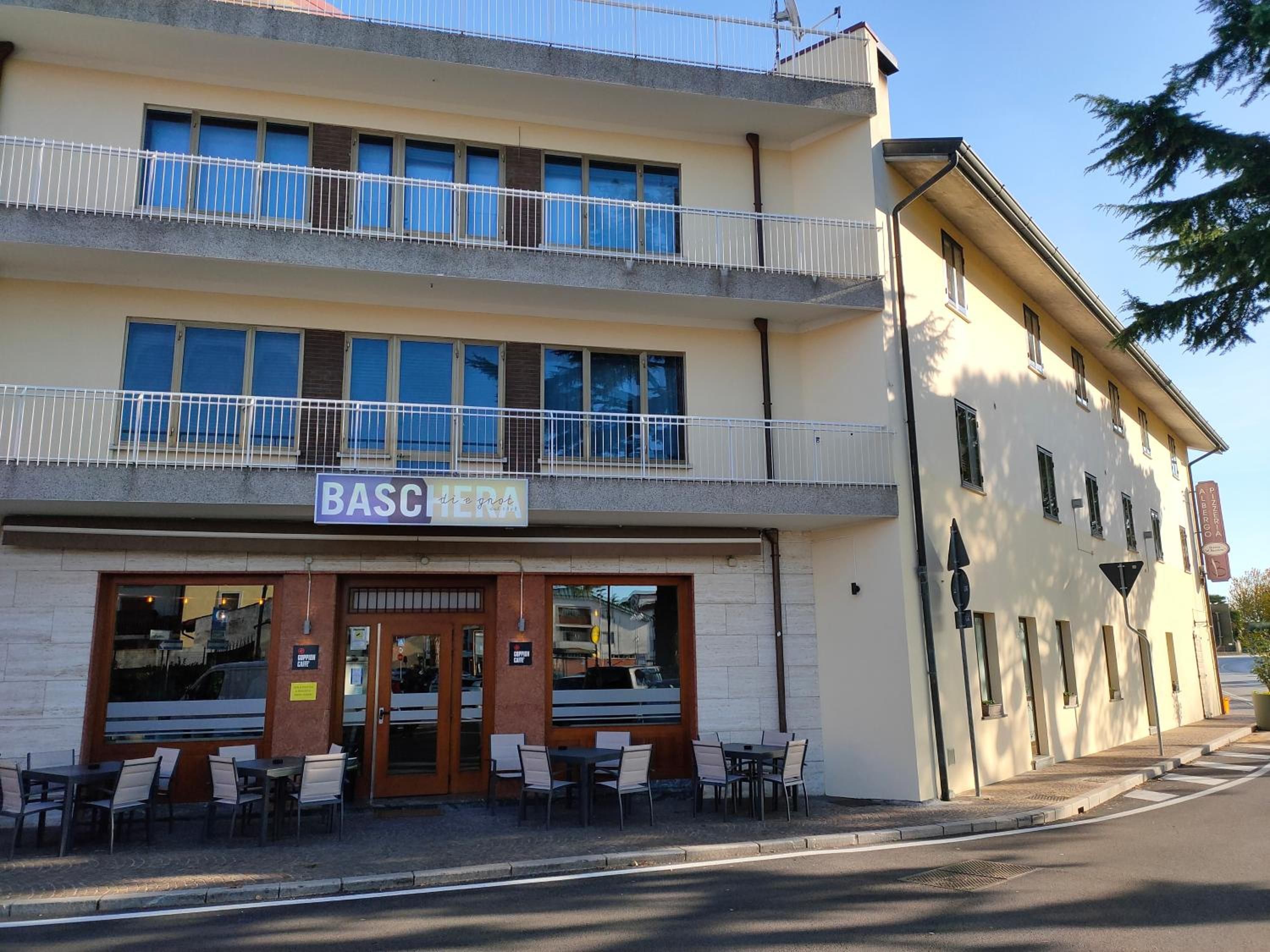 A building with a ground-floor restaurant named 'BASC HEERA' and a sign for 'PIZZERIA Aderio'.