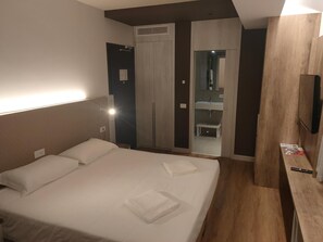 Ein Hotelzimmer mit Bett, Schrank, Spiegel und Fernseher.