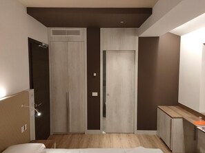 Ein modernes Schlafzimmer mit einem Bett, einem Kleiderschrank und einer kleinen Küchenzeile.