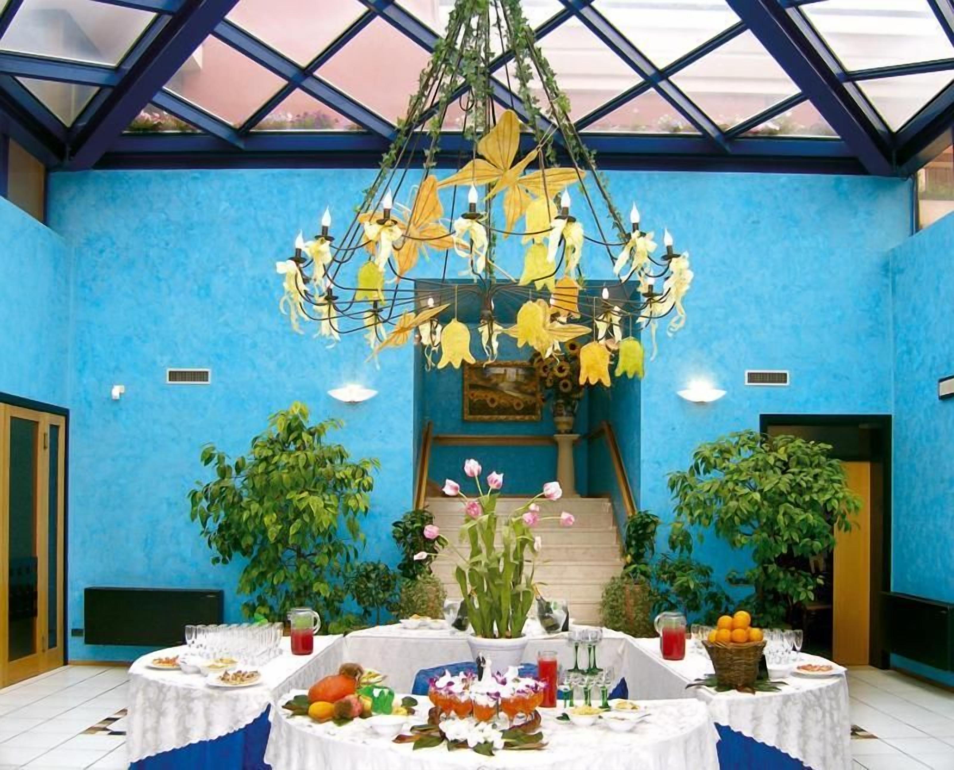 A dining area with a blue wall, a chandelier, and tables set for a meal.