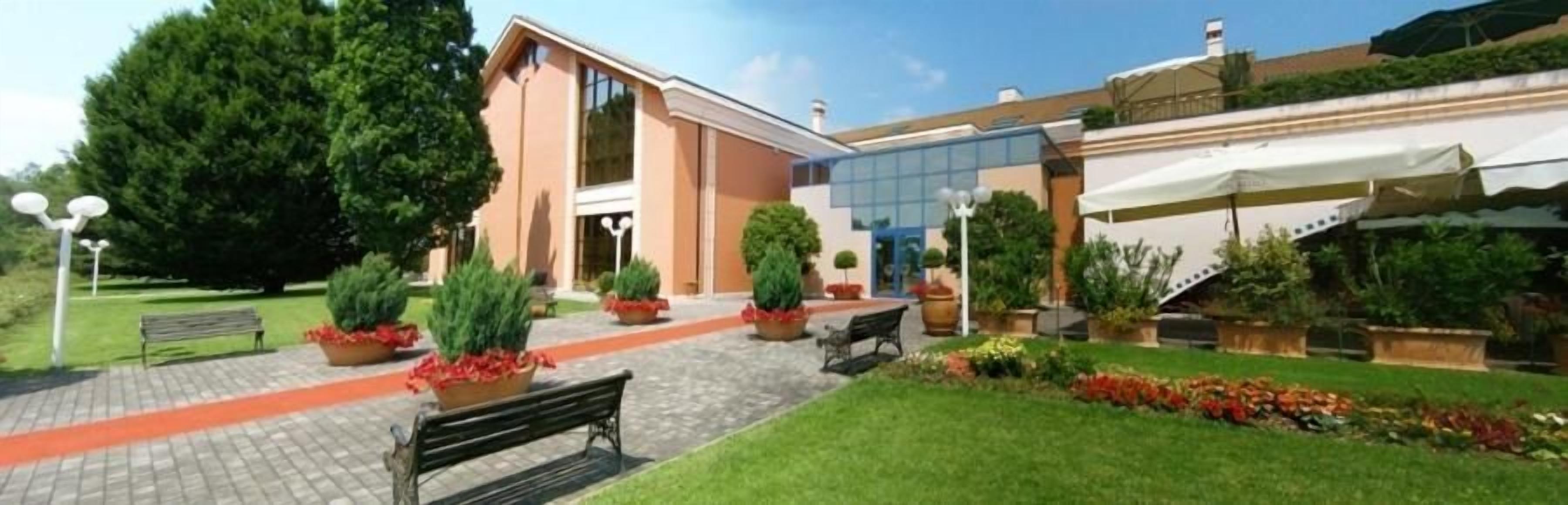A building with a paved entrance, outdoor seating, and potted plants.