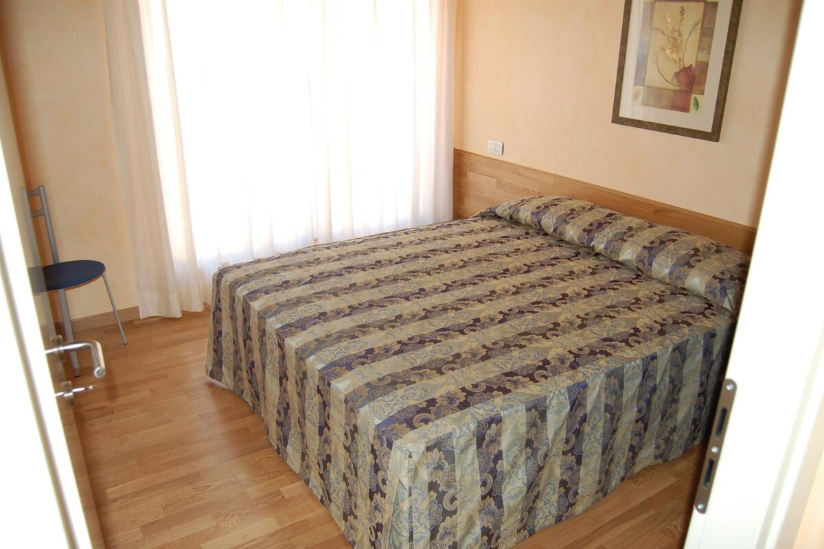 A bedroom with a bed, a chair, and a painting on the wall.