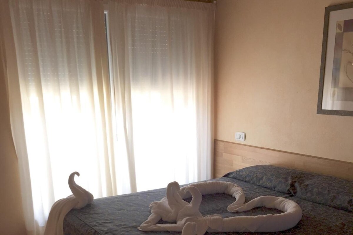 A bedroom with a bed, curtains, and a framed picture on the wall.