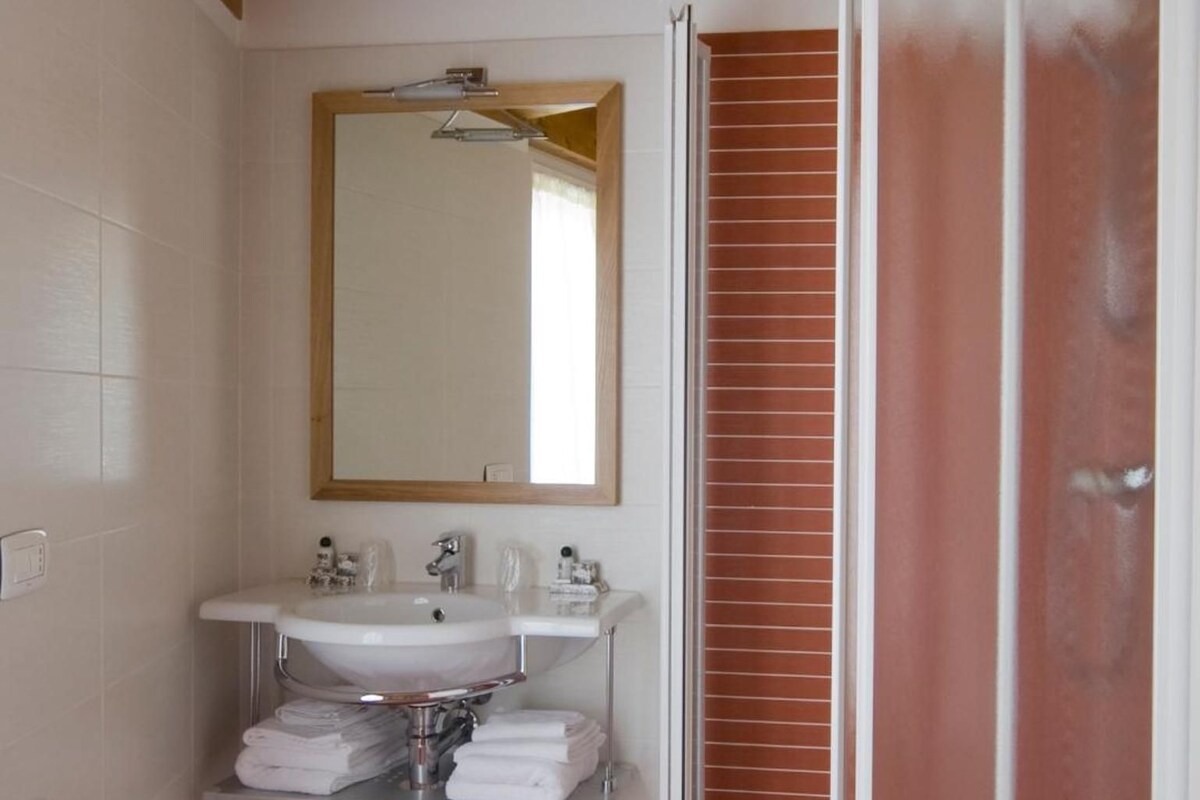 A bathroom with a white sink, mirror, and a shower enclosure.