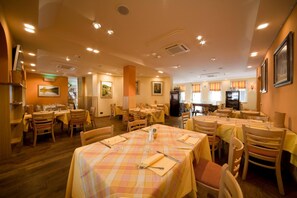 A restaurant with multiple dining tables, chairs, and a kitchen area.