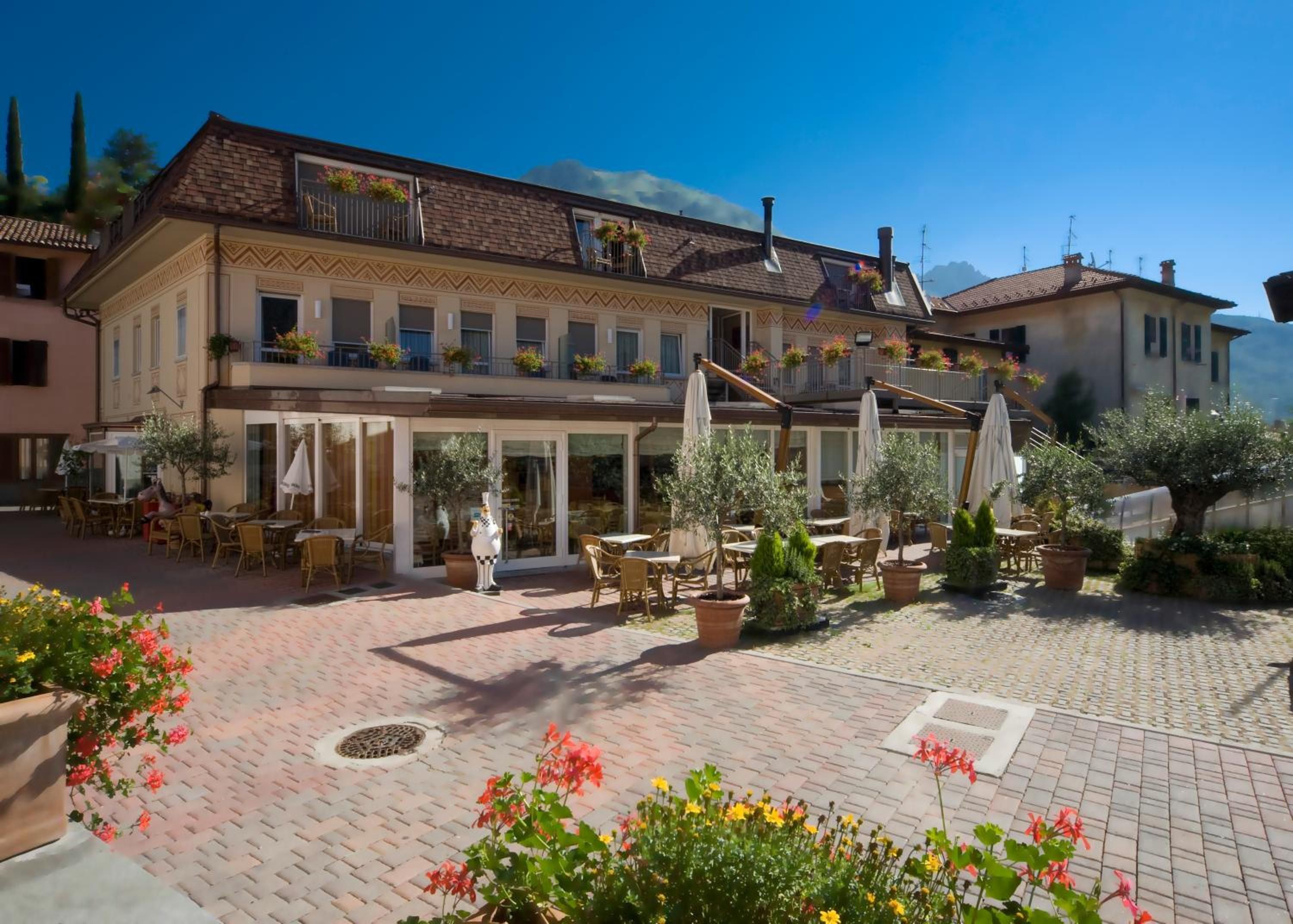 Un patio con mobiliario exterior, macetas con plantas y un edificio con balcones.