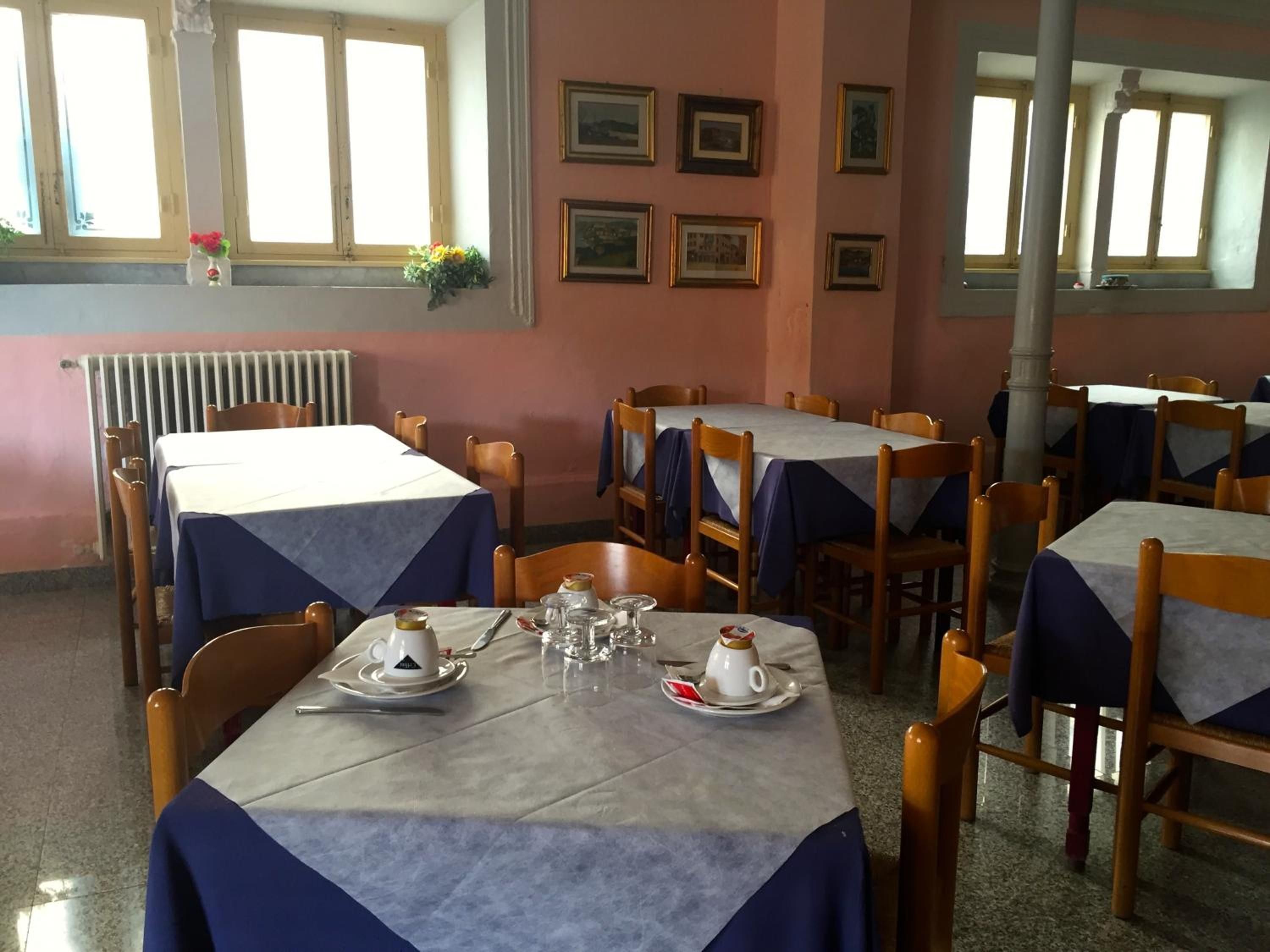A dining area with tables set for two, featuring a simple layout with chairs and basic table settings.