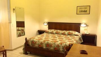A bedroom with a bed, bedside tables, a mirror, a lamp, and a framed picture on the wall.