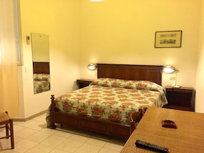 Ein Schlafzimmer mit Bett, Nachttischen, einem Spiegel, einer Lampe und einem gerahmten Bild an der Wand.