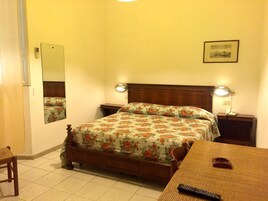 Un dormitorio con cama, mesitas de noche, un espejo, una lámpara y un cuadro en la pared.