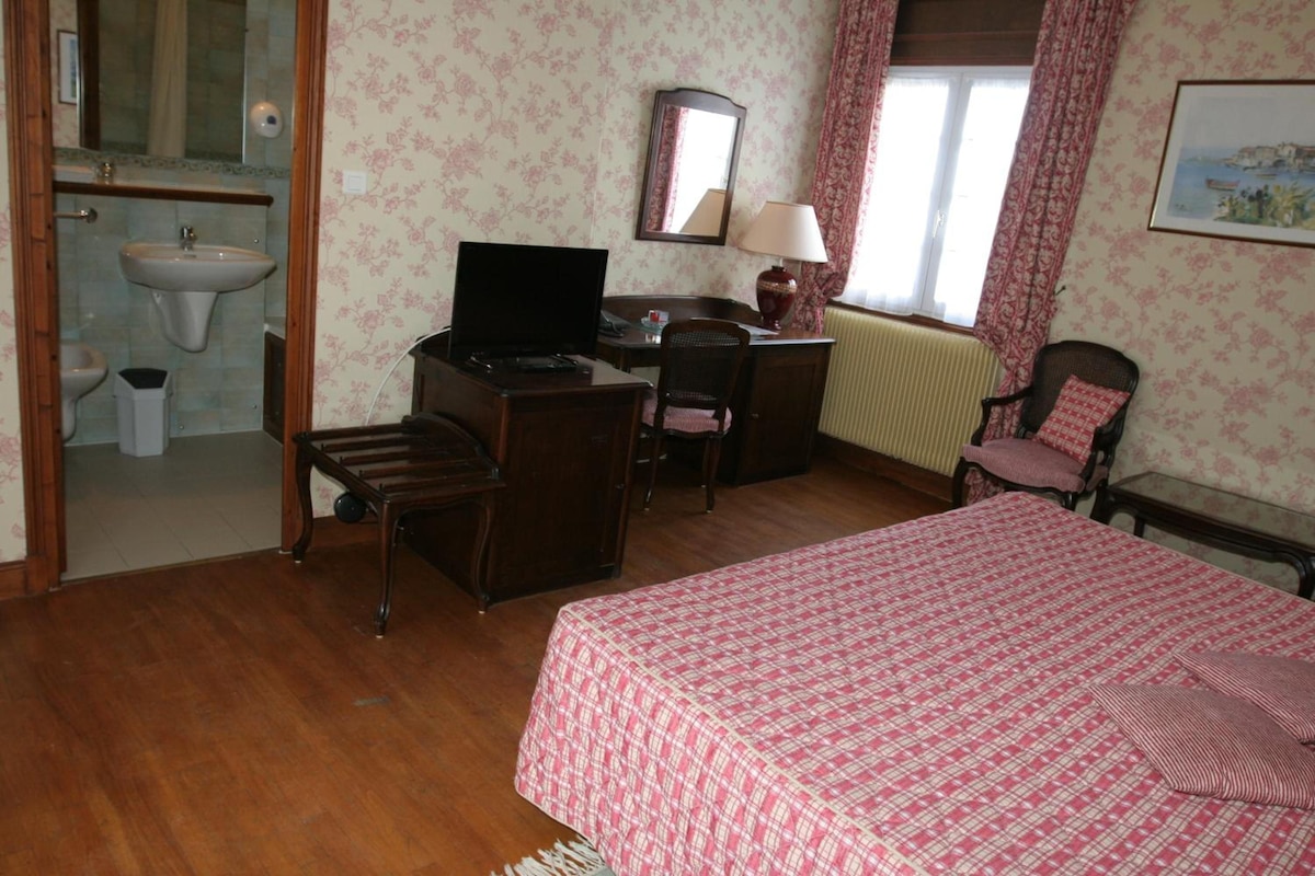 Una habitación de hotel con cama, escritorio, silla y televisor.
