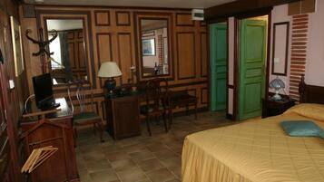 Habitación de hotel con cama, escritorio, sillas, un espejo y una puerta verde.