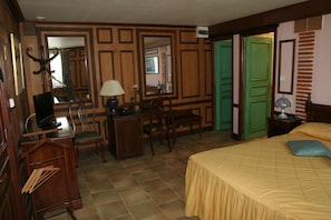 Habitación de hotel con cama, escritorio, sillas, un espejo y una puerta verde.