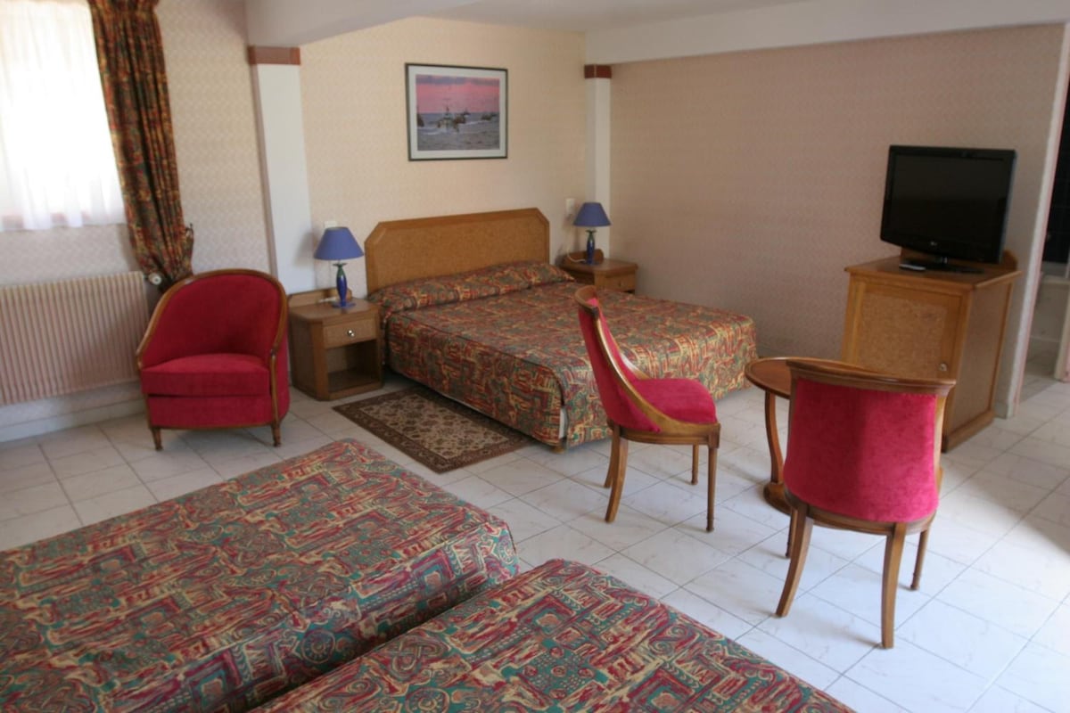 Una habitación de hotel con una cama, dos sillas, un televisor y un escritorio.