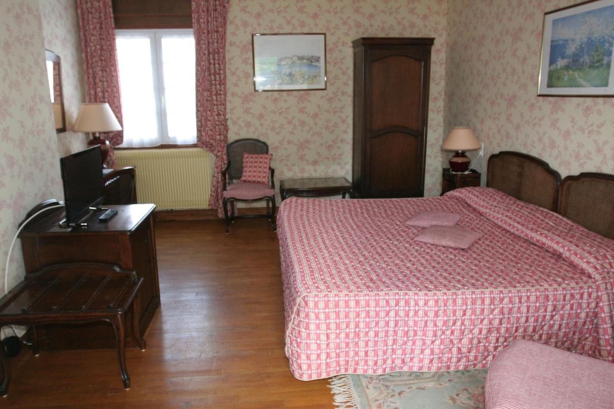 Un dormitorio con cama, escritorio, silla, radiador y ventana con cortinas.