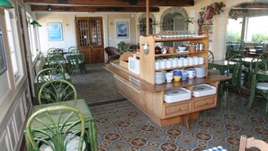 Un comedor con estación de servicio central, sillas verdes, baldosas de suelo con diseño y vista a través de un ventanal de arco.