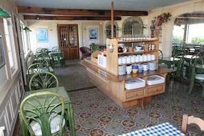 Un comedor con estación de servicio central, sillas verdes, baldosas de suelo con diseño y vista a través de un ventanal de arco.