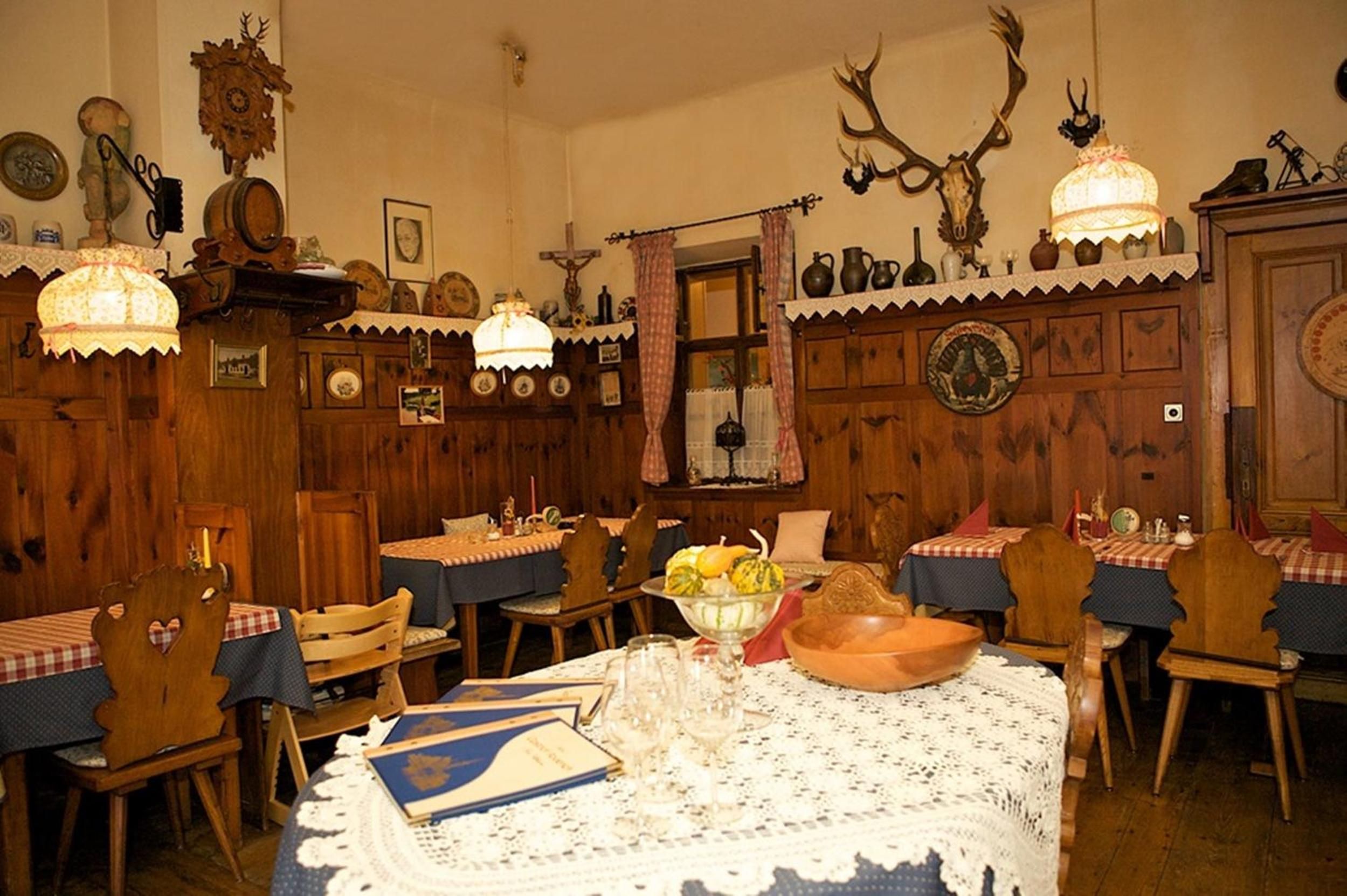 Comedor tradicional con paredes de madera, una araña y adornos de cuernos.