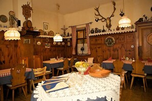 A traditional dining room with wooden walls, a chandelier, and antler decorations. - Gasthof Roderich Hotel (Langenzersdorf)