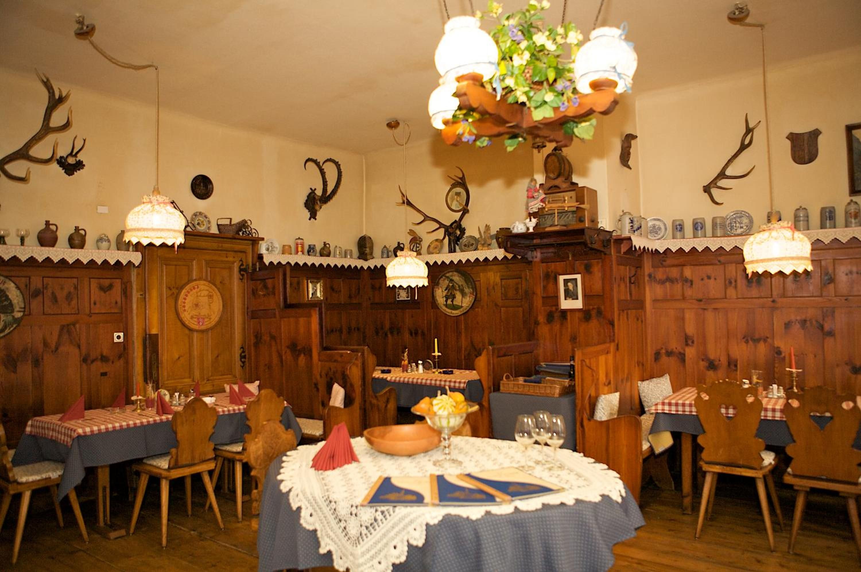 Ein Esszimmer mit Holzwänden, einer Kristallleuchtre und Geweihverzierungen.
