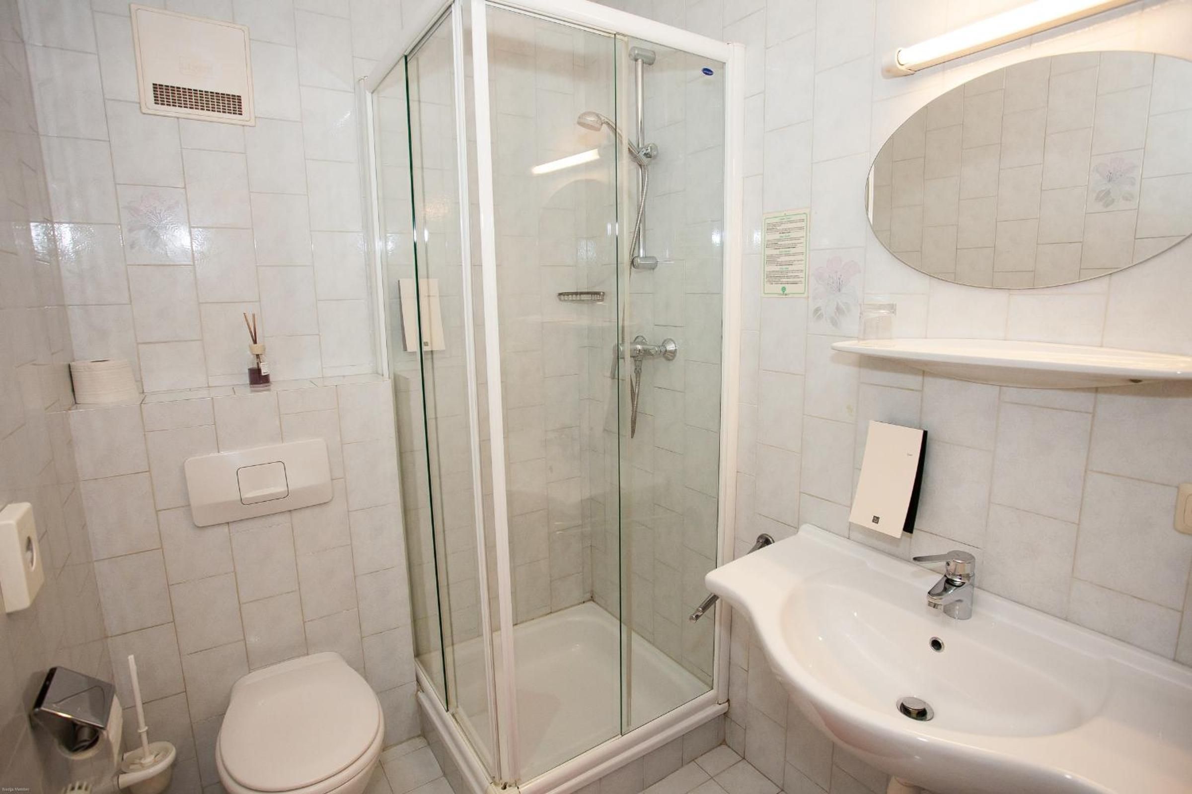 Ein Badezimmer mit einer Duschkabine, Toilette, Waschbecken und Spiegel.