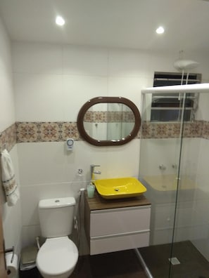 A bathroom with a toilet, a yellow sink, a mirror, and a glass shower enclosure. - Hostel Pousada Rheingantz Rio Grande (Rio Grande)