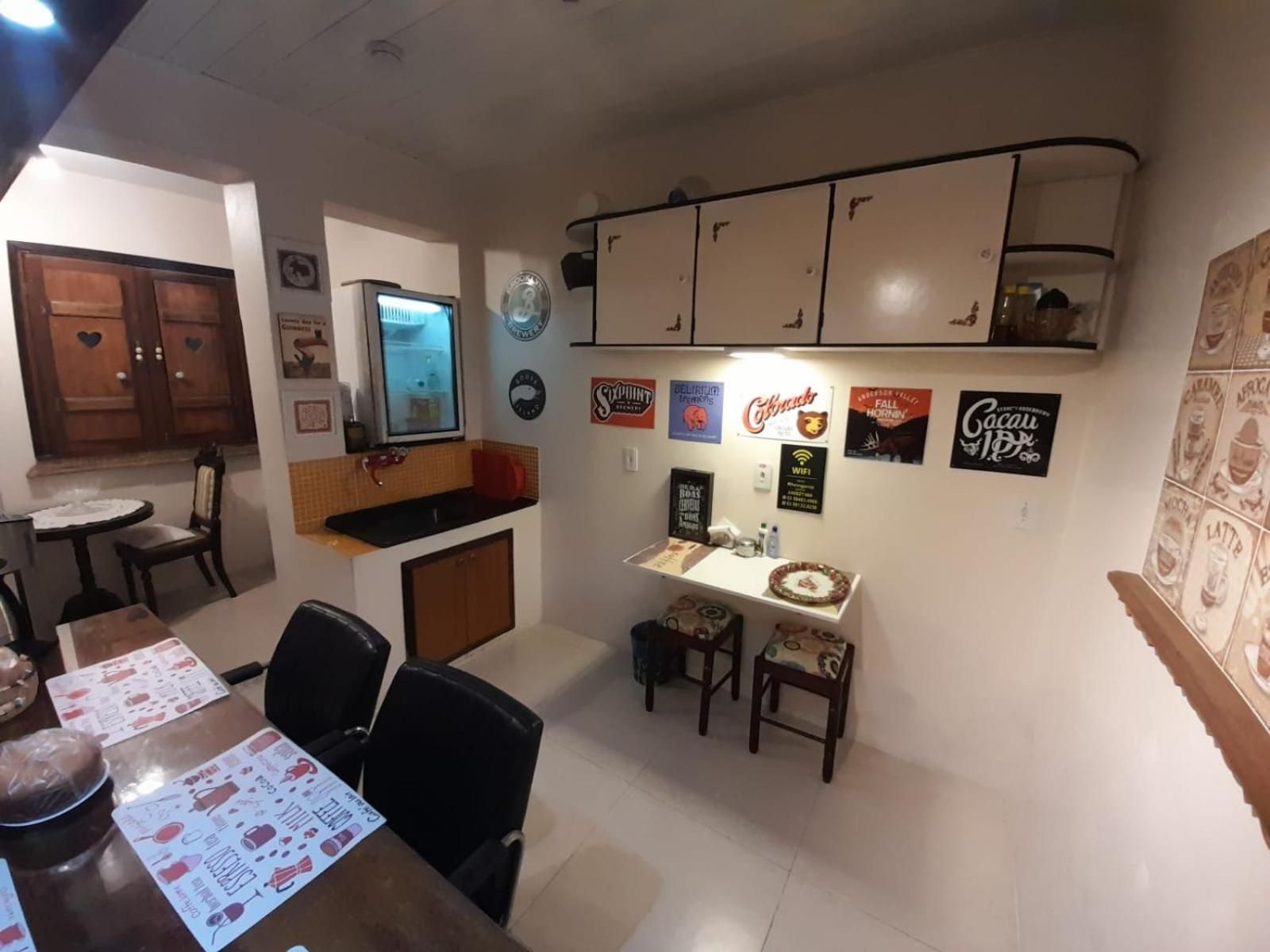 A dining area with a table, chairs, and a kitchen area with cabinets and a refrigerator.