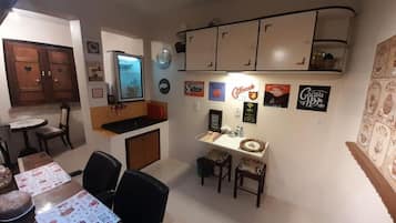 A dining area with a table, chairs, and a kitchen area with cabinets and a refrigerator.