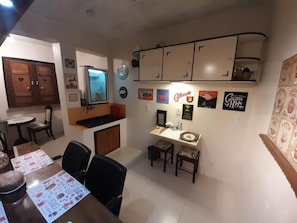 A dining area with a table, chairs, and a kitchen area with cabinets and a refrigerator. - Hostel Pousada Rheingantz Rio Grande (Rio Grande)