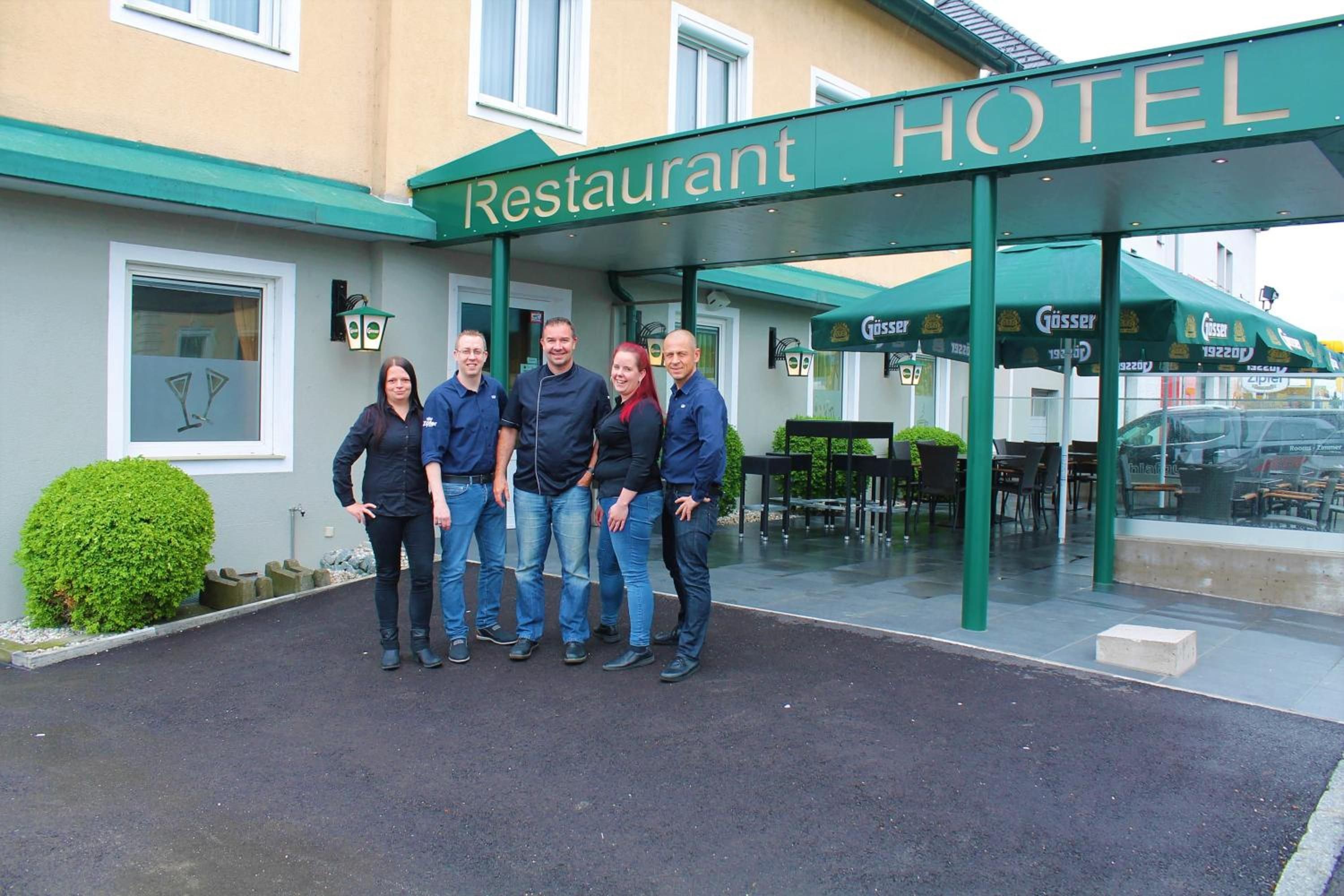 Ein Hotel Eingang mit einem Schild, das 'Restaurant HOTEL' zeigt, und eine Gruppe von Personen davor.
