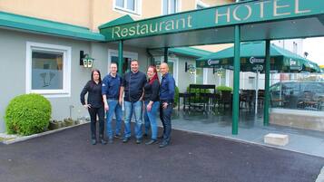Ein Hotel Eingang mit einem Schild, das 'Restaurant HOTEL' zeigt, und eine Gruppe von Personen davor.