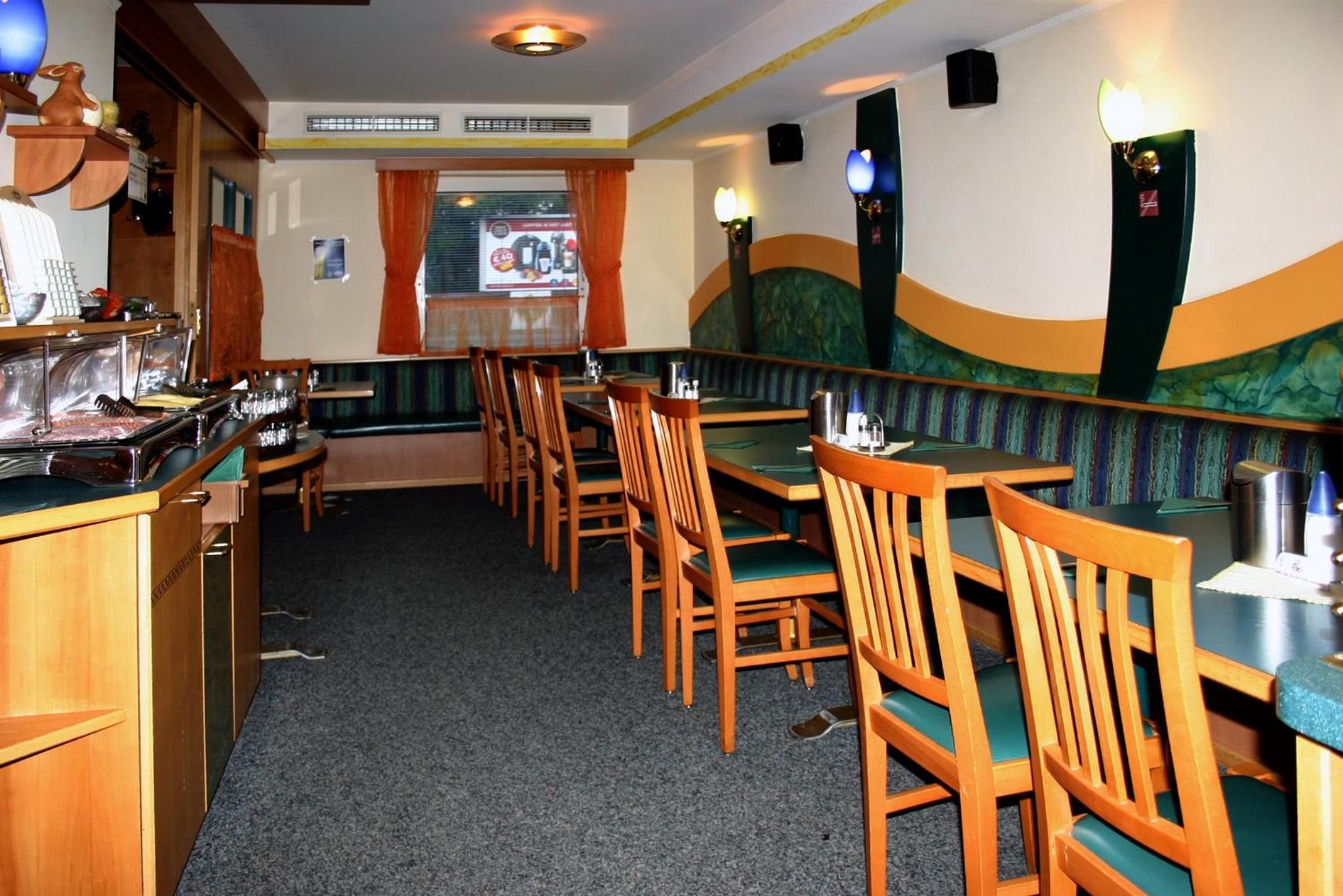 Ein Restaurant mit Sitzboxen und Tischen, Holzsesseln, einem Buffetbereich und Blick aus dem Fenster.