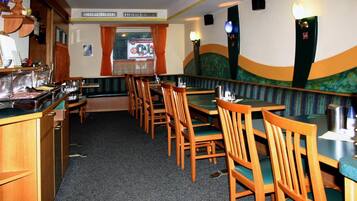 Ein Restaurant mit Sitzboxen und Tischen, Holzsesseln, einem Buffetbereich und Blick aus dem Fenster.