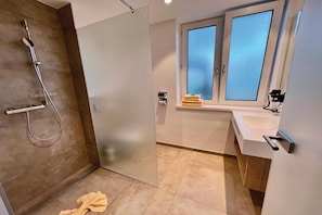 Un baño con ducha, lavabo y ventana.